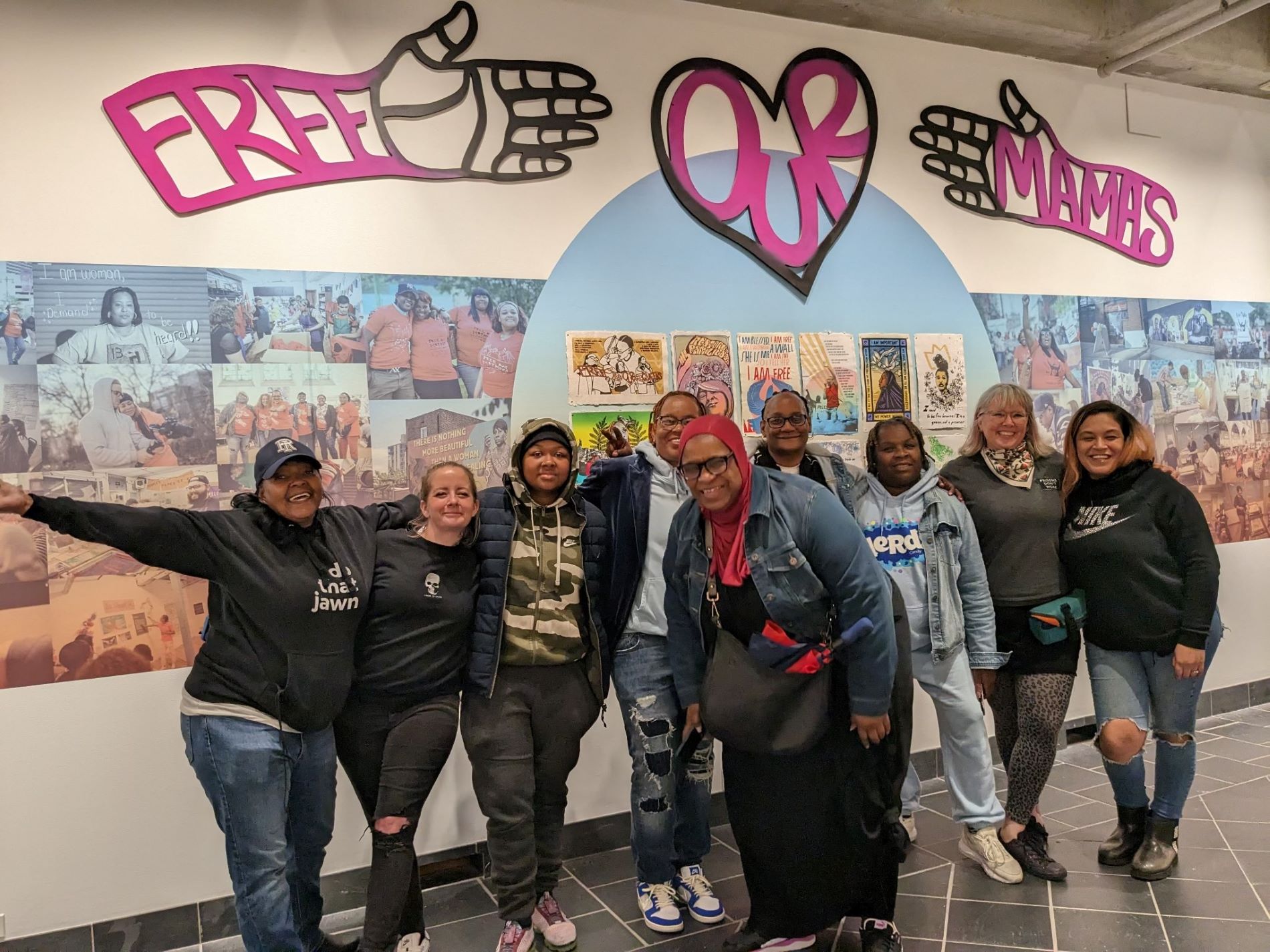 Kali poses with 8 other women in front of a sign that says free our mamas