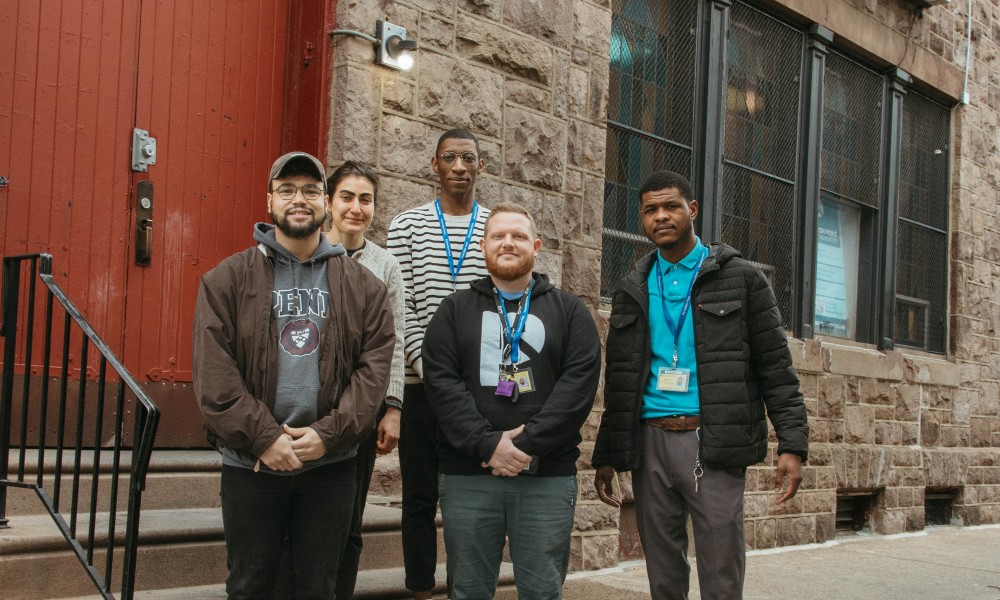 Five staff stand in front of a red door outside